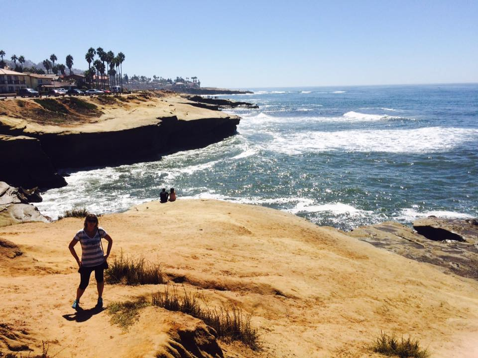 Helen på klippene ved Sunset Cliffs med havet og palmer i bakgrunnen
