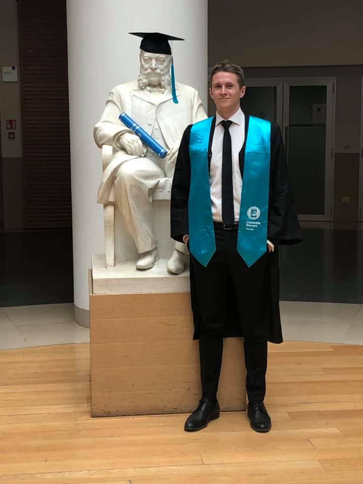 Edvin i kappe og turkis stjal ved siden av Bocconi-statuen