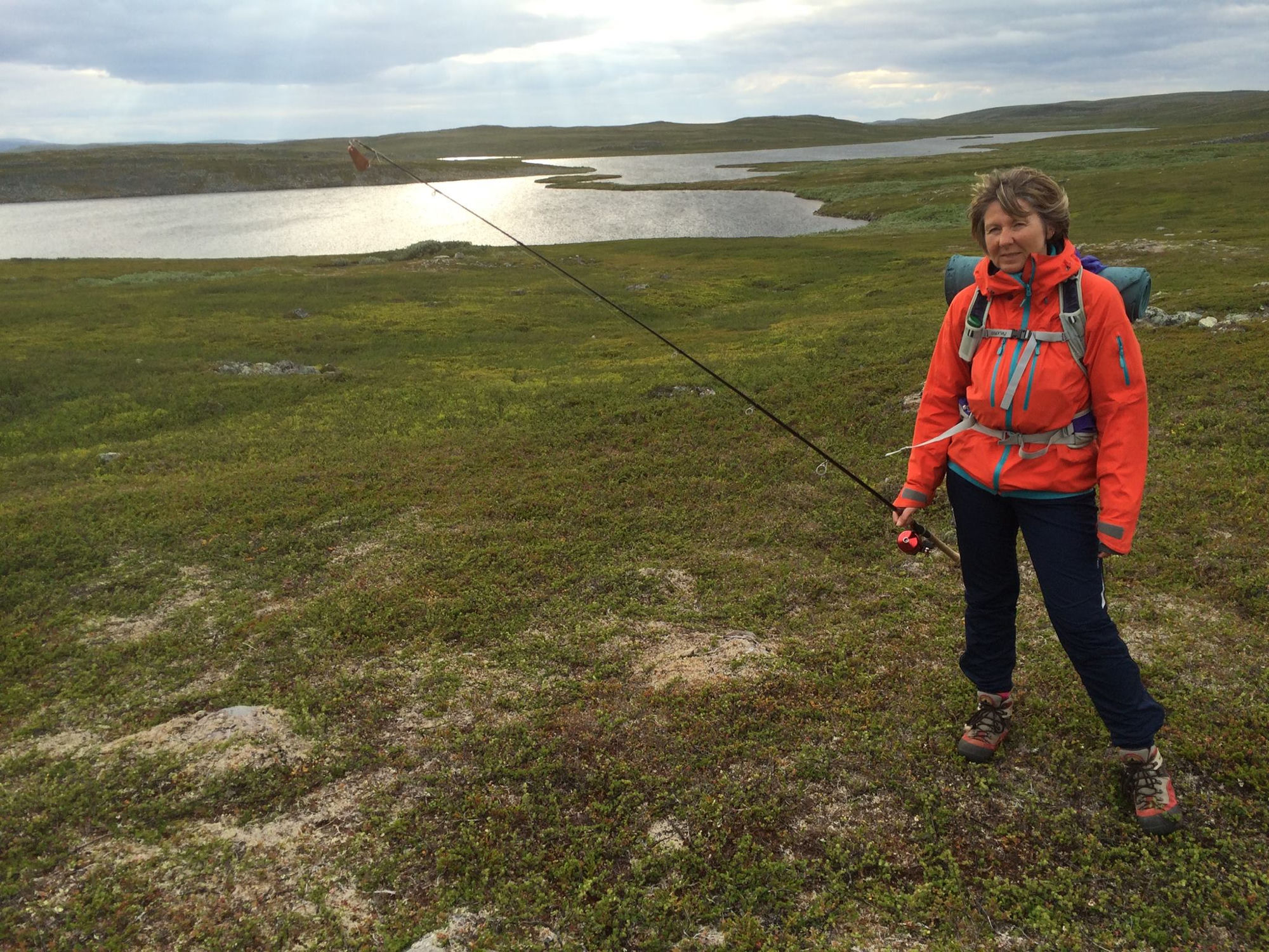 Helen med fiskestang og ryggsekk ved vannet