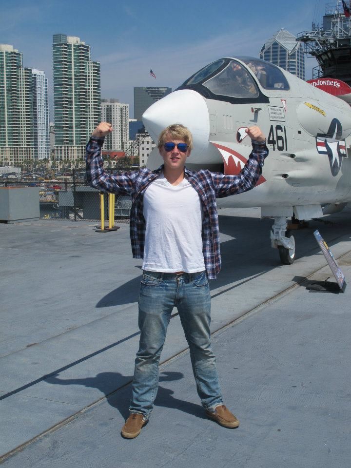 Sønn poserer foran et jagerfly på USS Midway