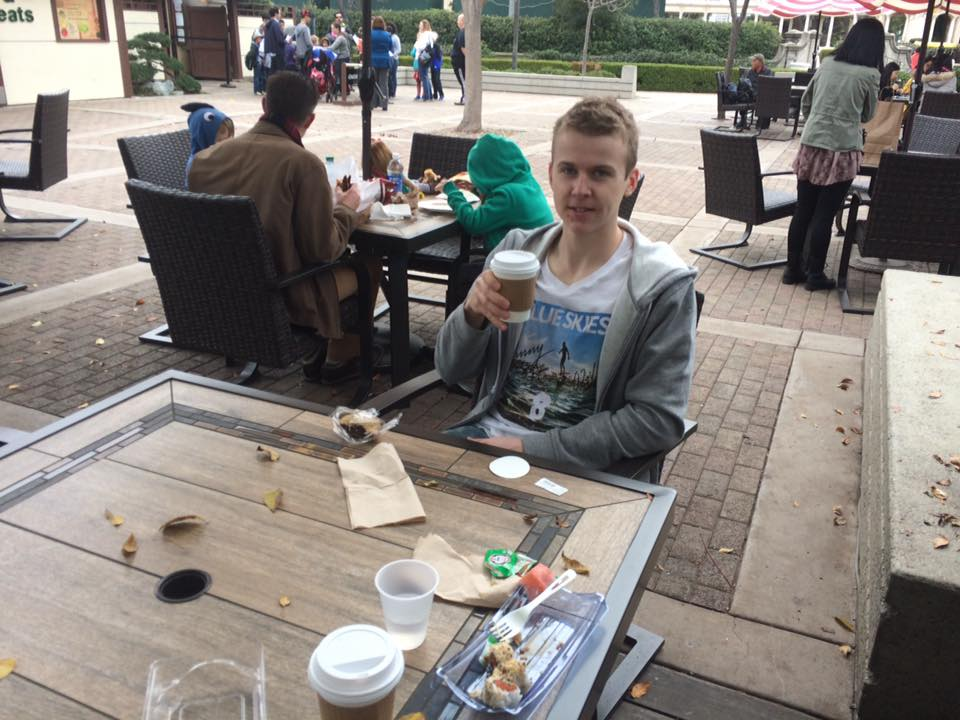 Aksel sitter ute med kaffekopp og bakverk